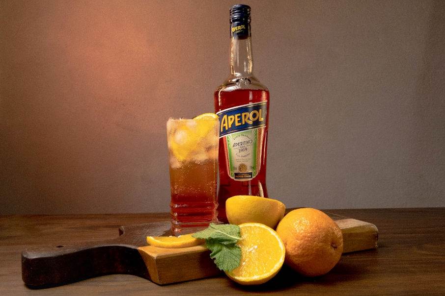 negroni kokteilis ar aperol pudeli uz galda